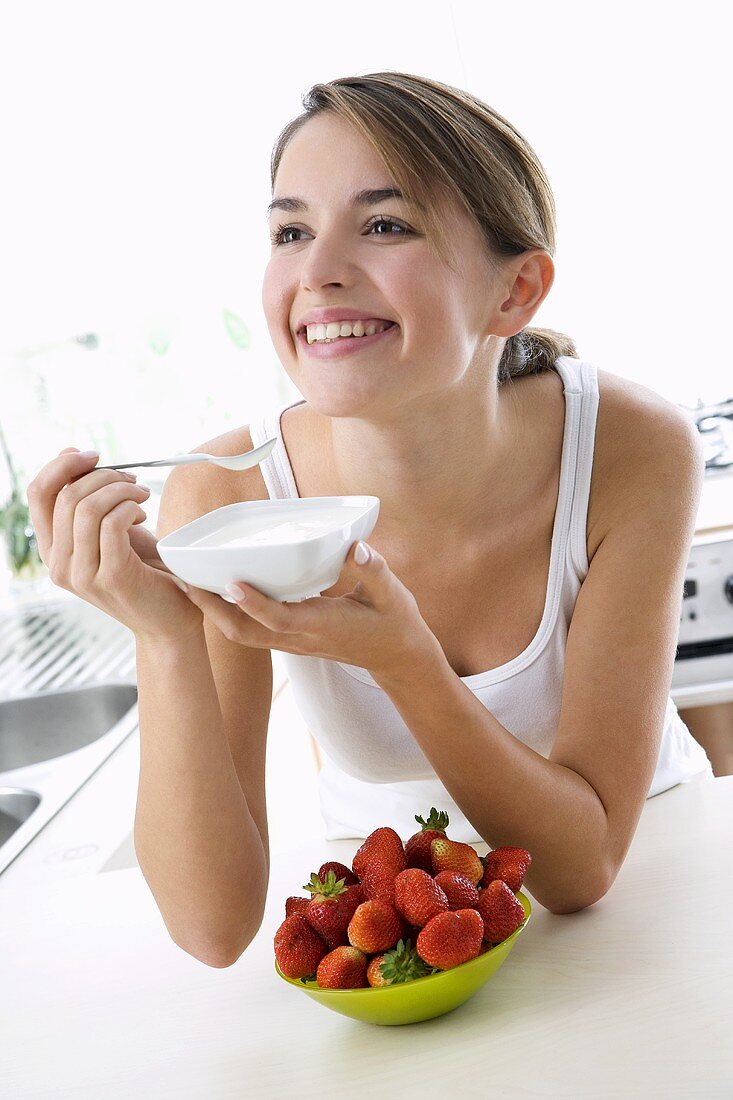 Young woman eating yoghurt out of a small bowl