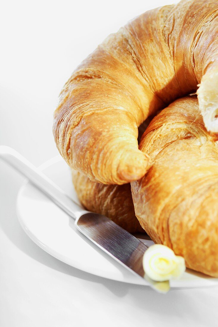 Croissants auf einem Teller mit Messer und Butter