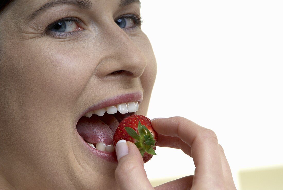 Woman biting into a strawberry