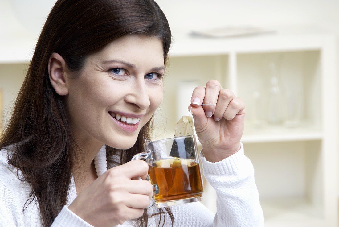 Woman holding cup of tea and tea bag in her hands