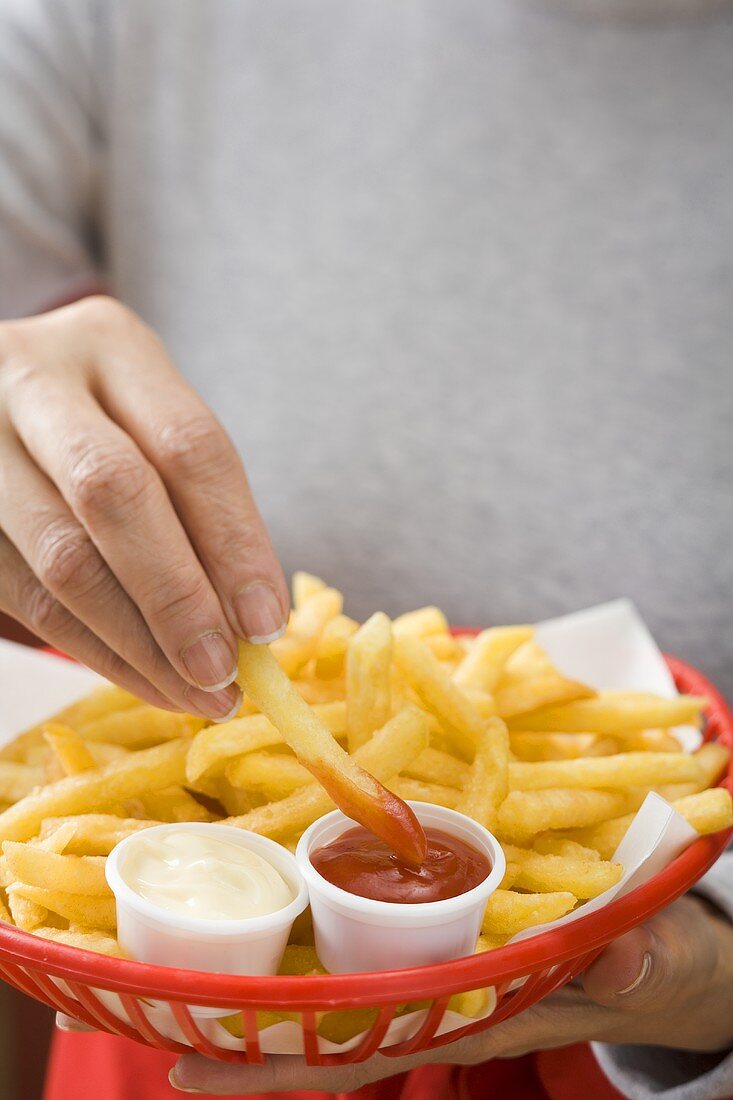 Chips with ketchup and mayonnaise in small basket