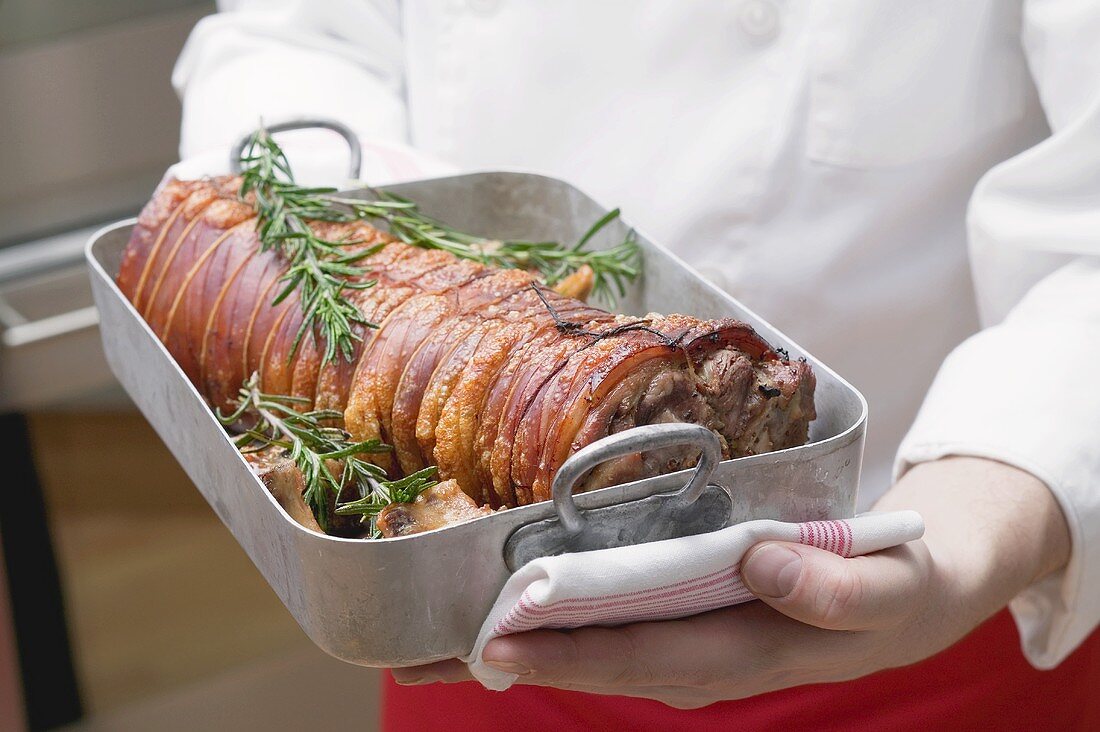 Rolled saddle of suckling pig in roasting tin with rosemary