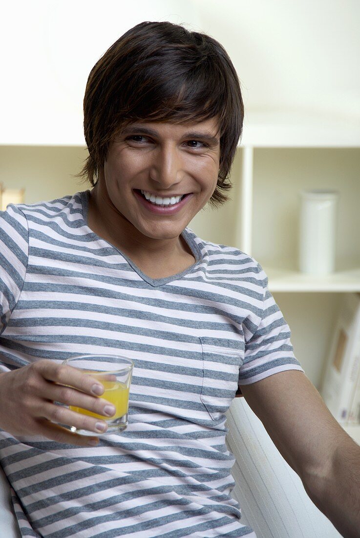 Junger Mann hält ein Glas Saft in der Hand