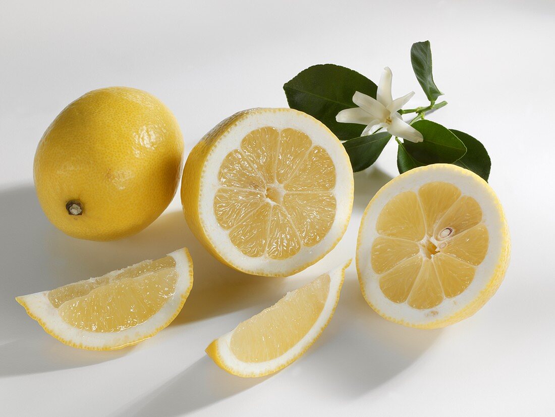 Ganze und halbierte Zitrone mit Zitronenspalten