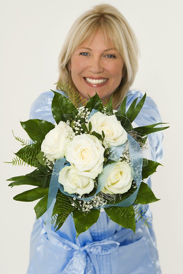 Smiling woman showing bouquet of white roses