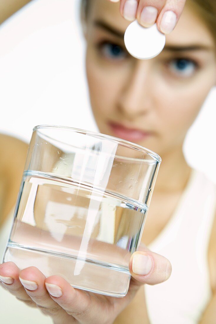 Woman dropping an effervescent tablet into a glass of water