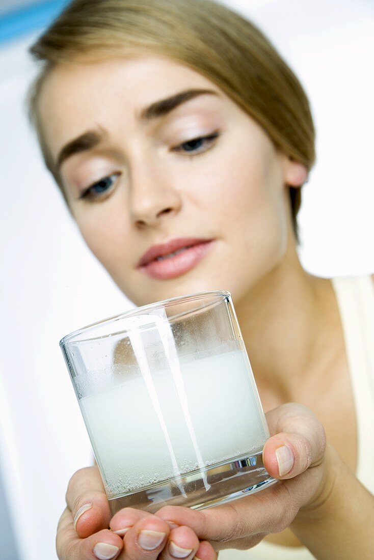 Woman looking at dissolved effervescent tablet in a glass