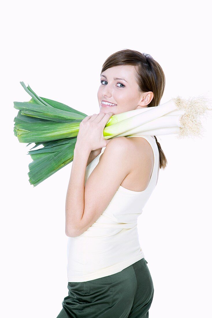 Young woman carrying fresh leeks on her shoulder