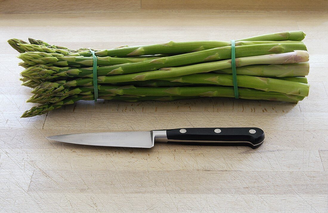 A bundle of green asparagus with knife