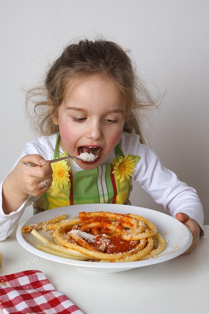 Small girl eating macaroni with tomato sauce and Parmesan