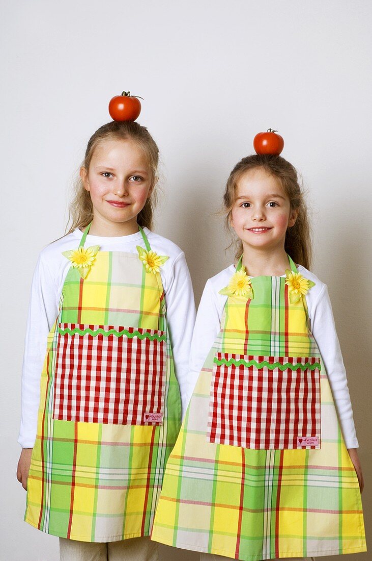 Zwei Mädchen mit Tomaten auf dem Kopf