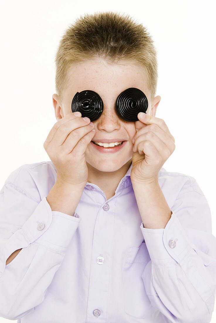 Junge hält zwei Lakritzschnecken vor die Augen
