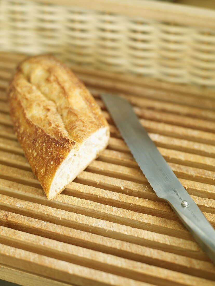 A piece of baguette with knife in a bread basket