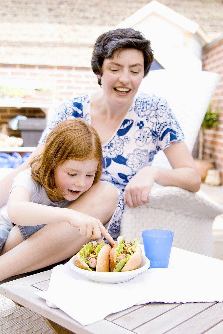 Frau & kleines Mädchen mit zwei Hot Dogs