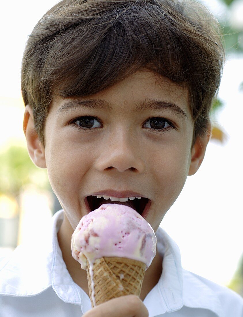 Junge isst eine Kugel Erdbeer-Vanille-Eis in der Waffel