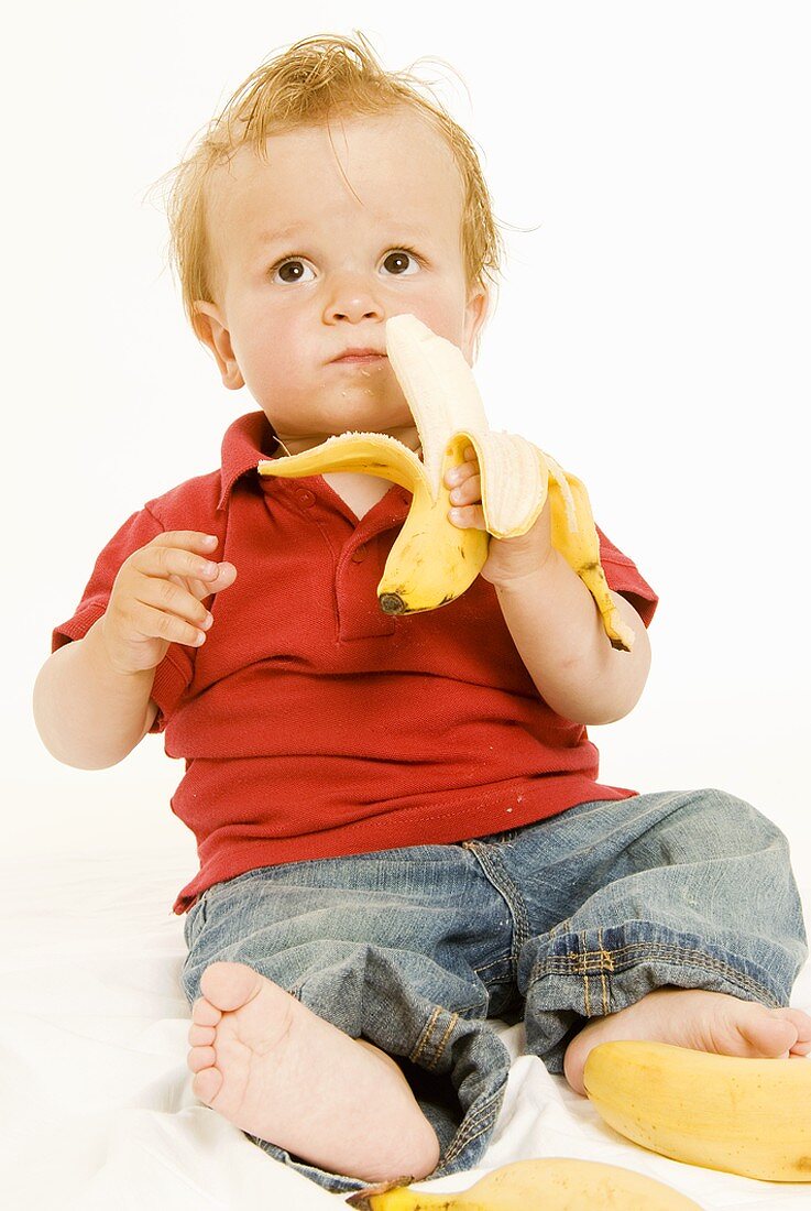 Small boy holding a banana in his hand