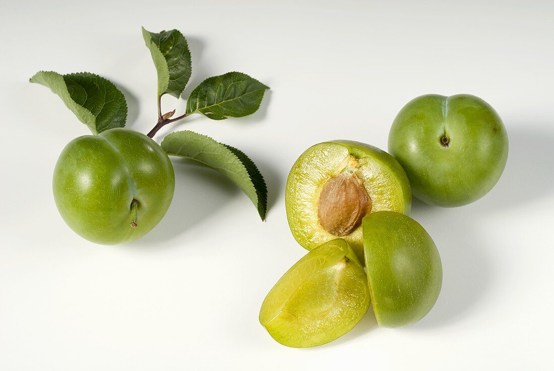 Whole and half greengages with leaves