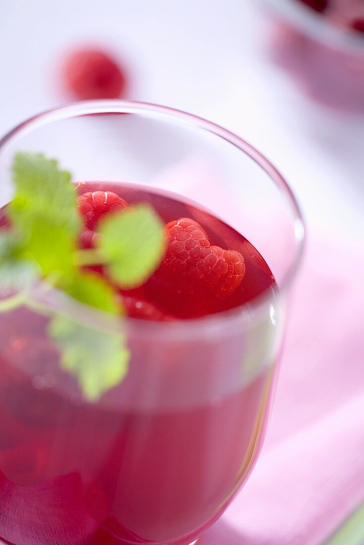 A glass of raspberry juice with fresh raspberries