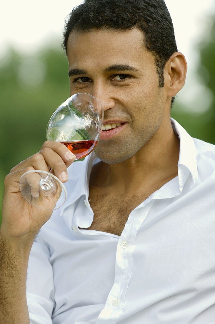 Junger Mann trinkt ein Glas Rosewein