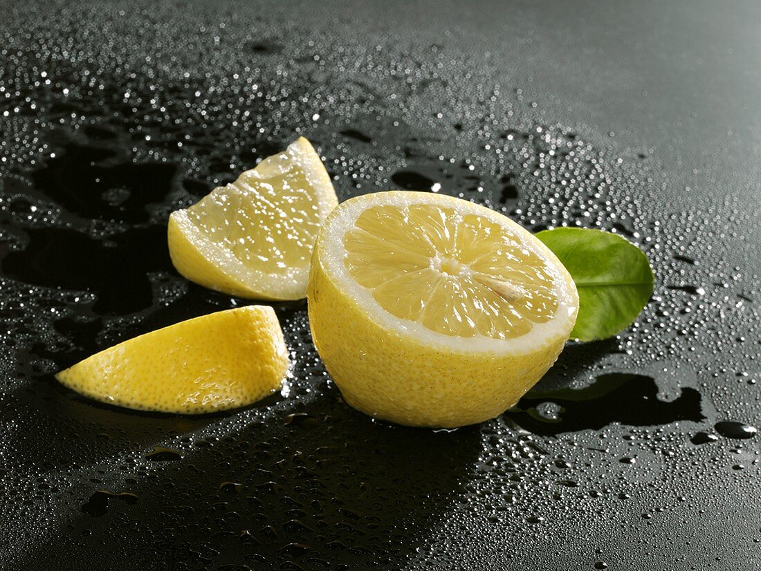 Halbe Zitrone und zwei Zitronenspalten