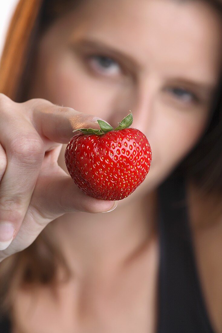 Young woman holding a strawberry
