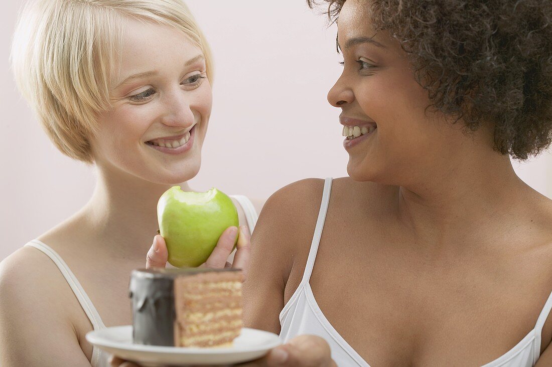 Two young women with apple and cake