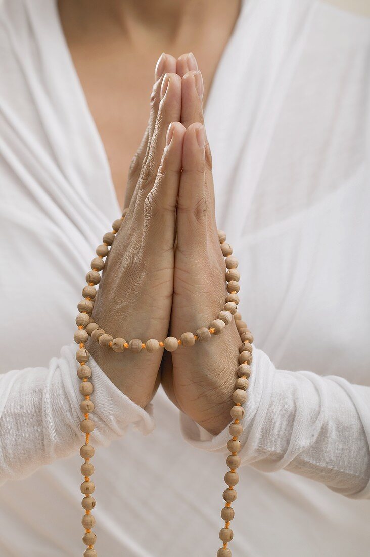 Junge Frau mit gefalteten Händen beim Meditieren