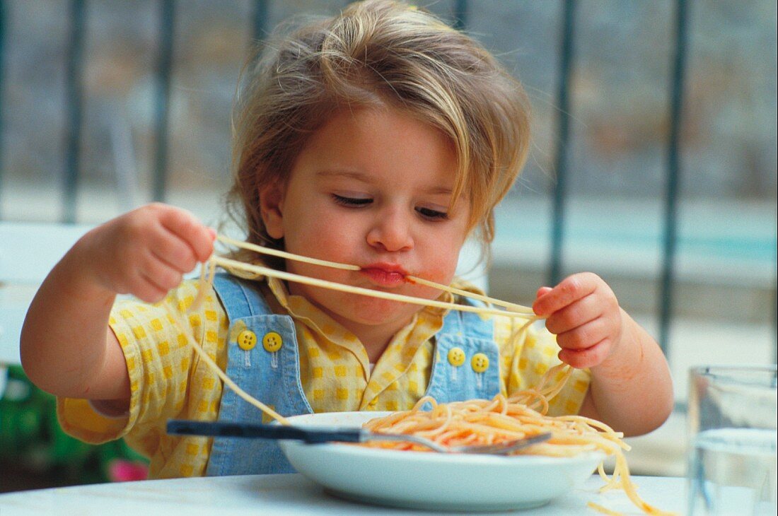 Mädchen isst Spaghetti mit Tomatensauce