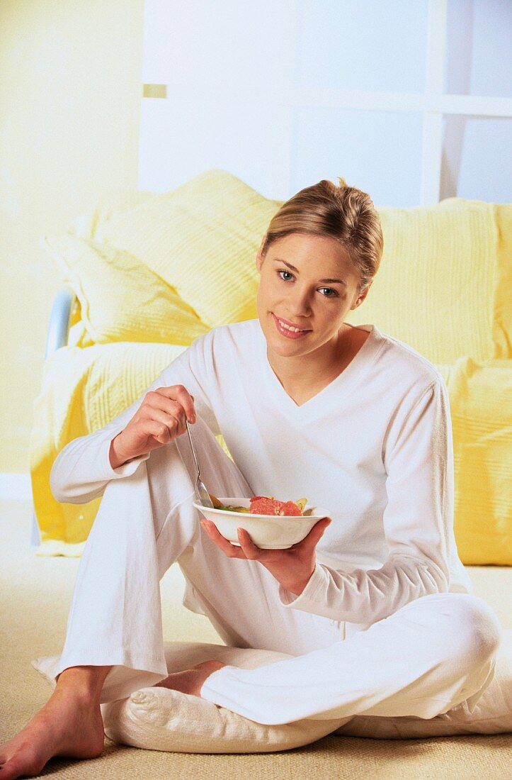 Happy woman eating fruit salad