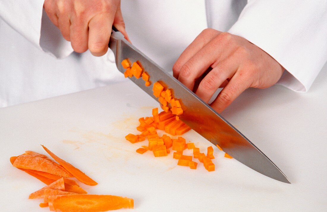 Carrots being diced with a knife