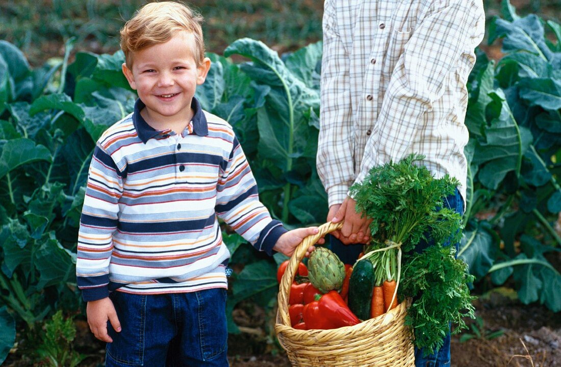 Zwei Jungen tragen einen Korb mit Gemüse