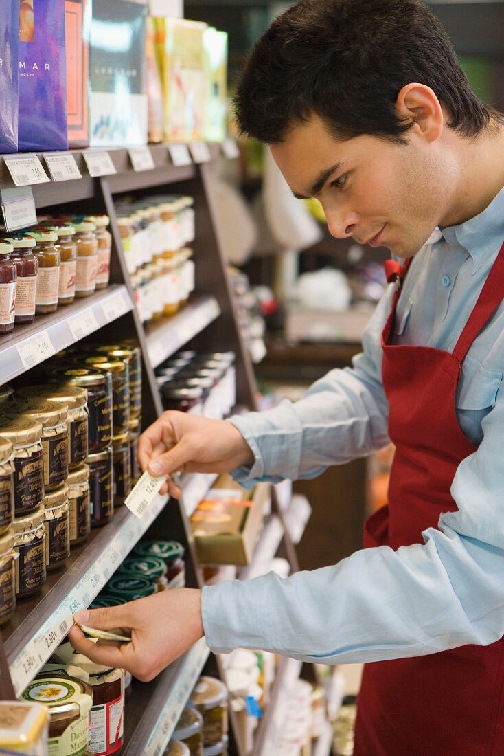 Mann beim Etikettieren der Regale im Supermarkt