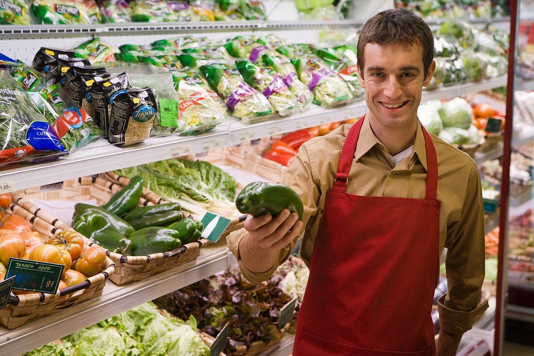 Verkäufer in einem Supermarkt an der Gemüsetheke