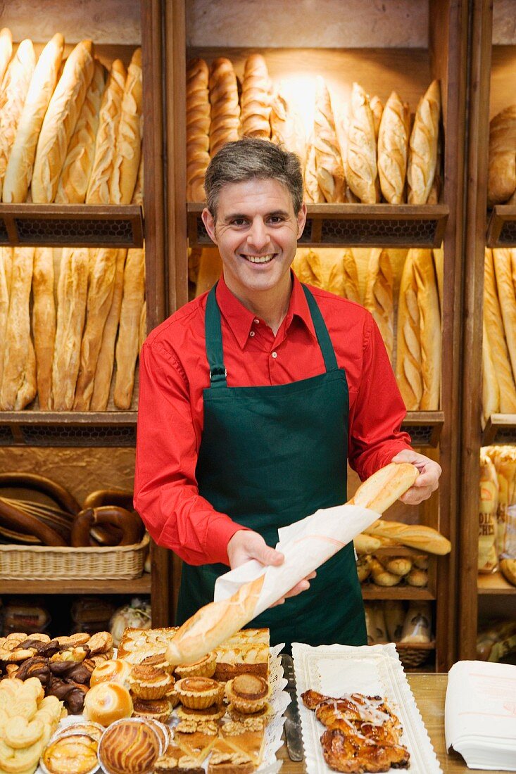 Verkäufer packt Baguette in einer Bäckerei ein