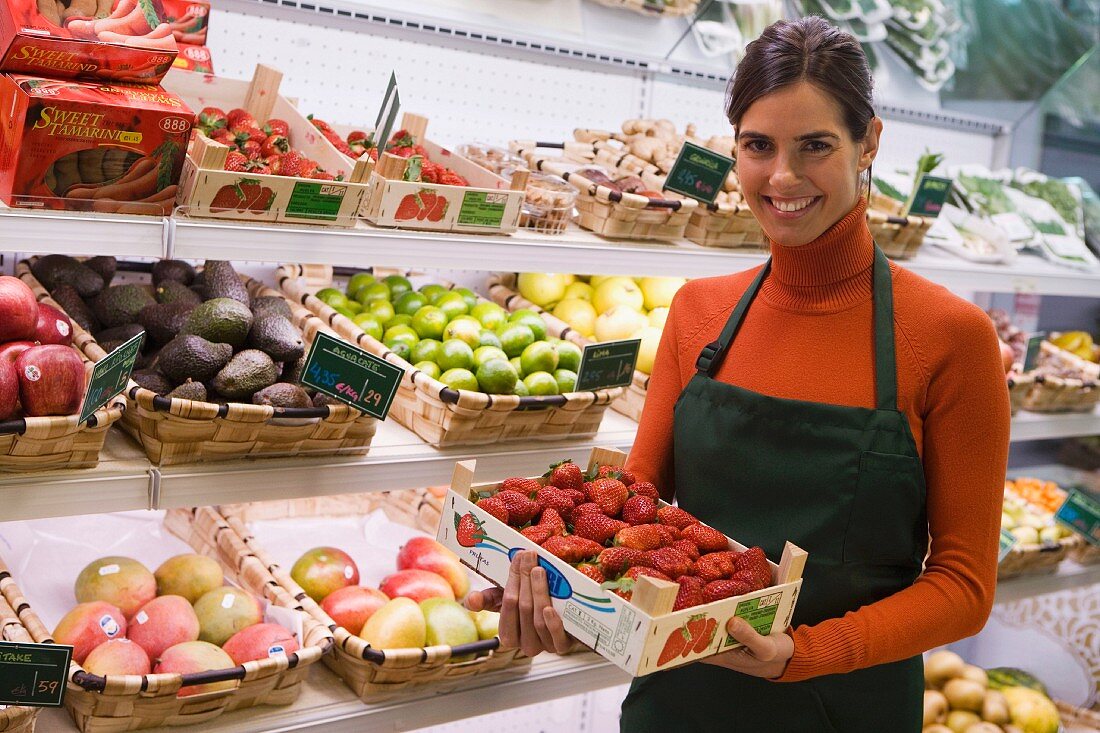 Verkäuferin im Supermarkt mit Steige Erdbeeren