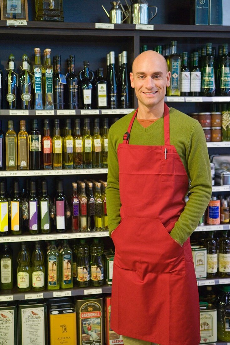 Sales assistant in front of shelves of olive oil
