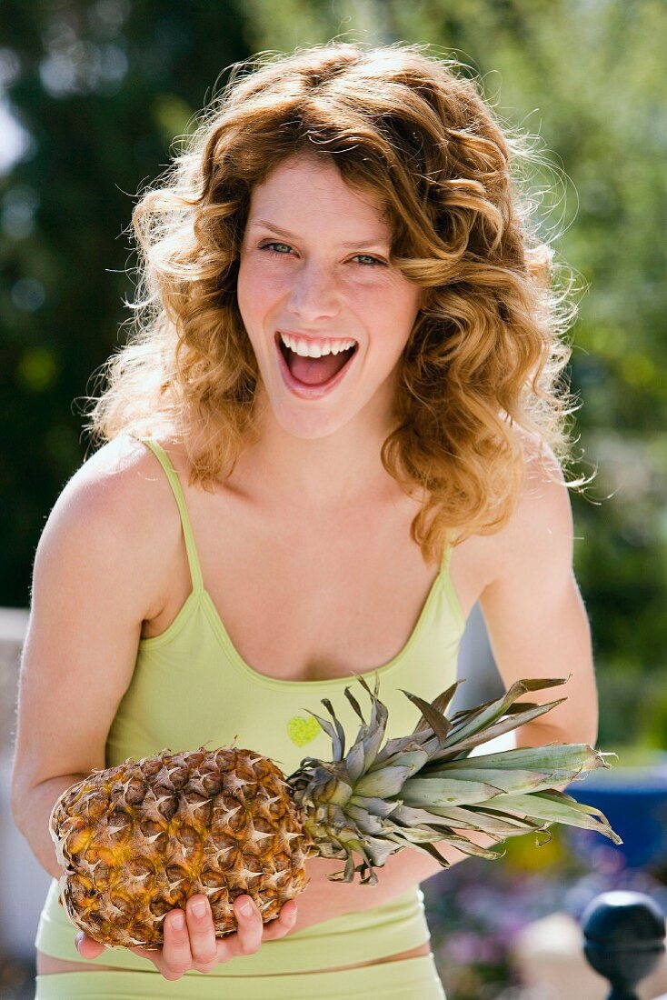 Lachende Frau mit einer Ananas