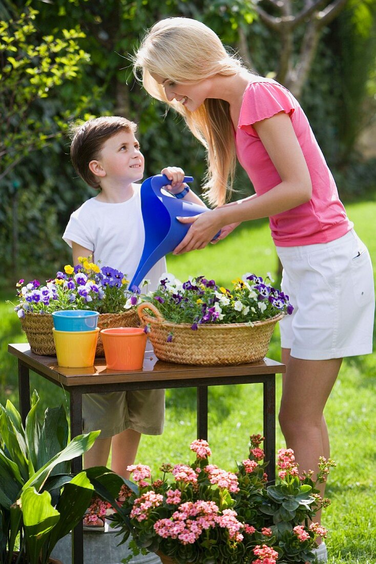 Mutter und Sohn beim Blumen gießen