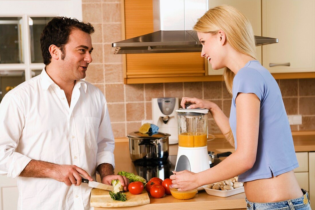Man and woman making vegetable puree in kitchen