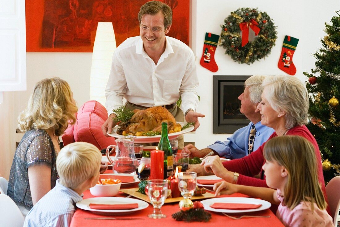 Familie beim Weihnachtsessen, Vater hält Truthahn