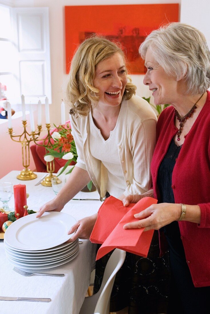 Frau mit Mutter beim Eindecken des Tisches zu Weihnachten