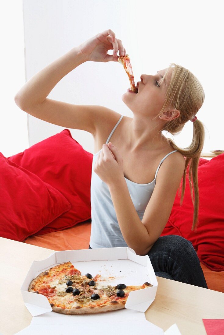 Seated woman eating pizza from pizza box