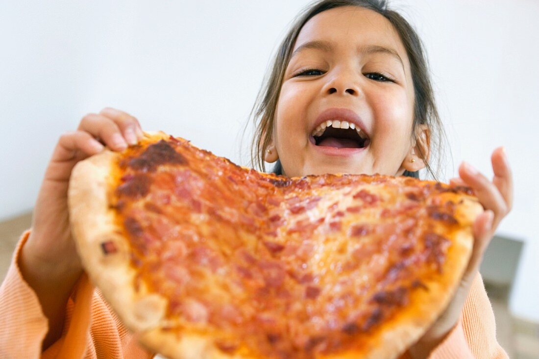 Girl biting into whole pizza