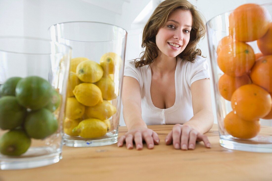 Frau am Tisch sitzend mit Gläser voll Zitrusfrüchte