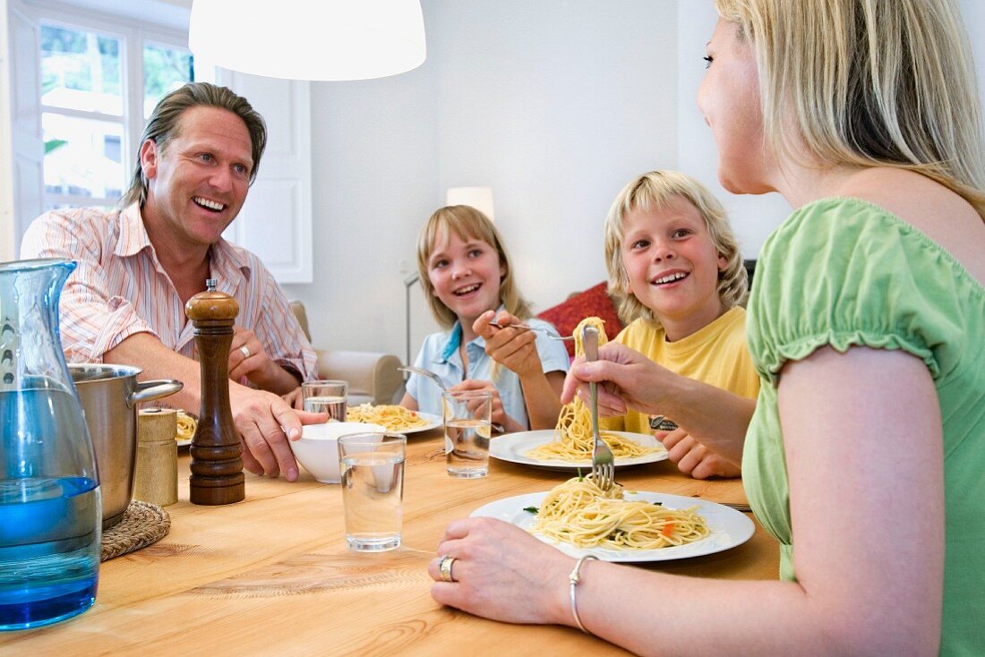 Family eating spaghetti in dining room