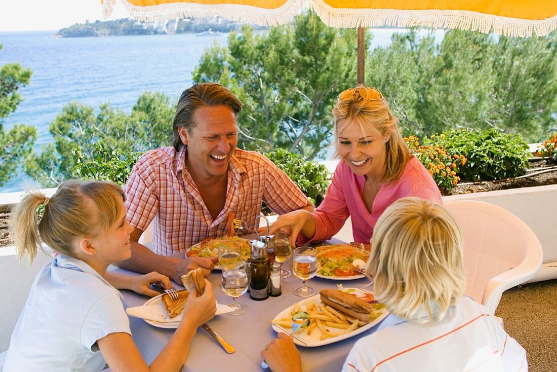 Familie beim Mittagessen im Urlaub am Meer