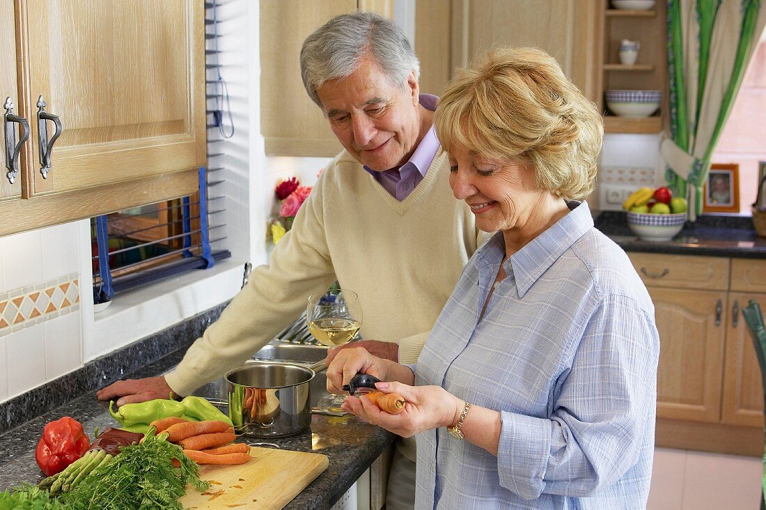 Older couple chopping vegetables in kitchen