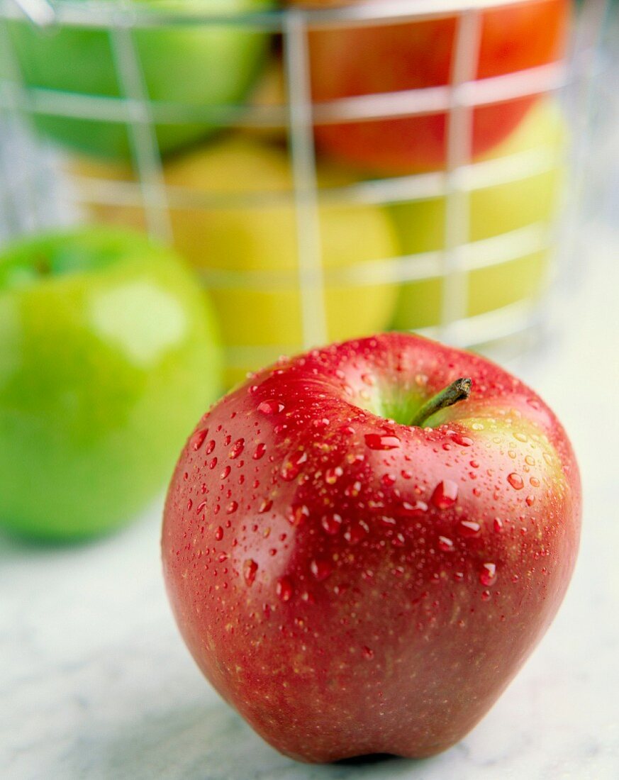 Ein Apfel der Sorte Gala vor einem Körbchen mit Äpfeln