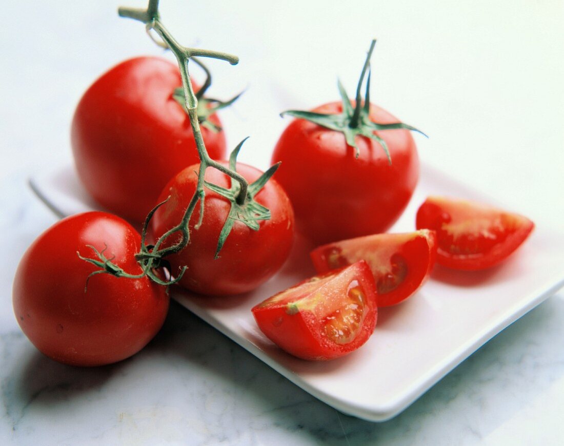 Mehrere frische Strauchtomaten und Tomatenviertel