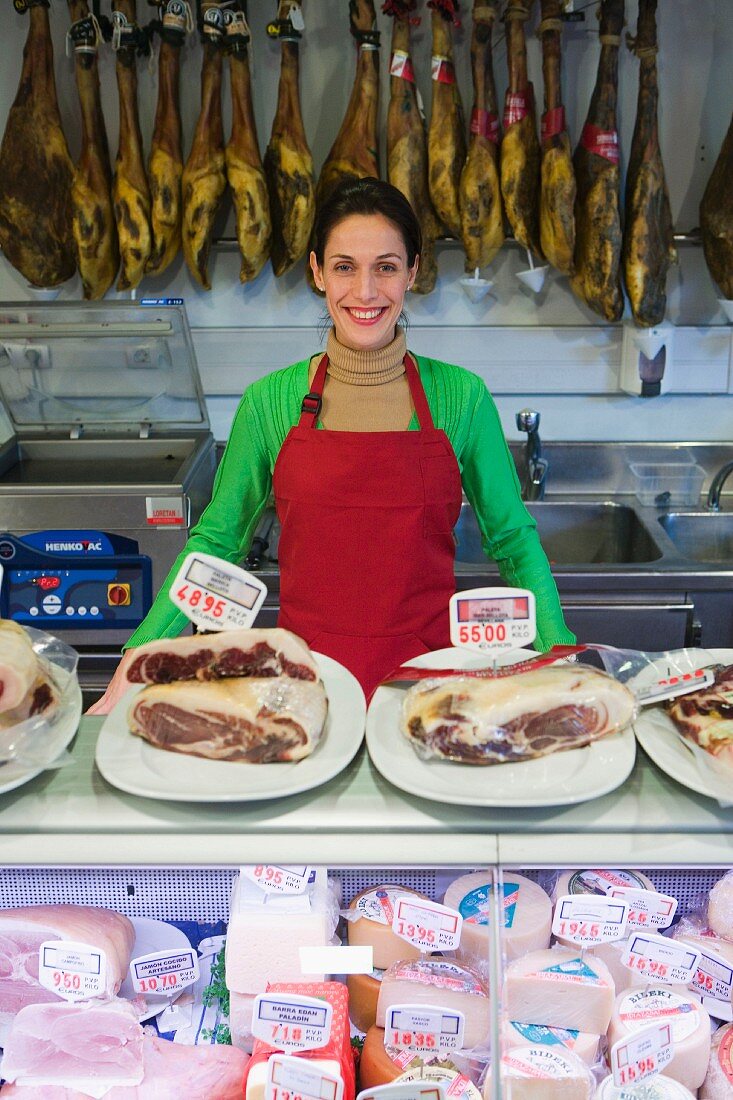 Verkäuferin im Supermarkt hinter der Käse- und Wursttheke